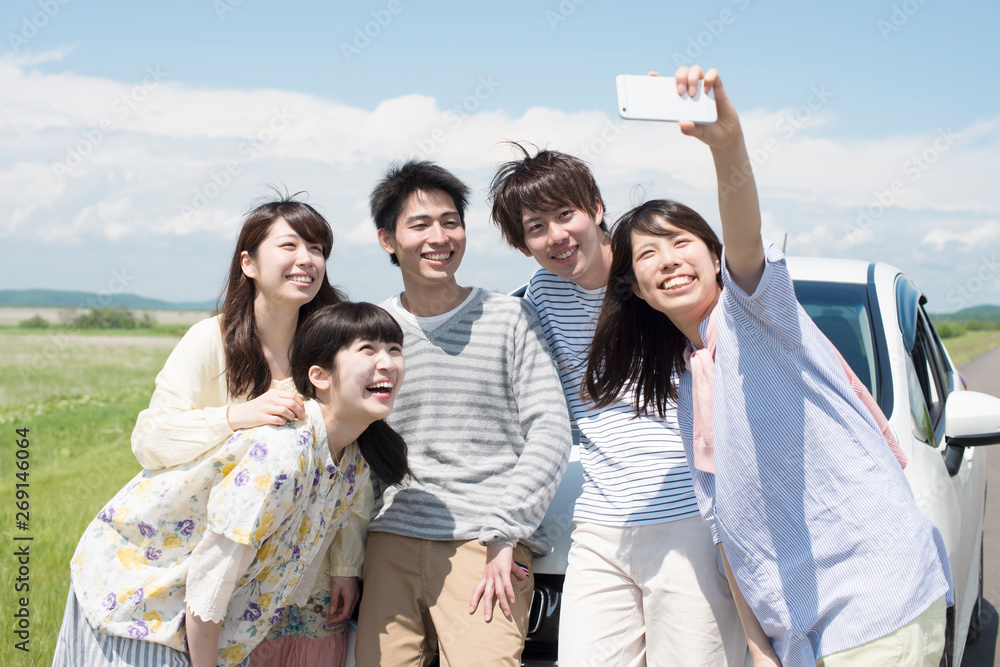 車の前で自撮りする旅系クリエイターのグループ